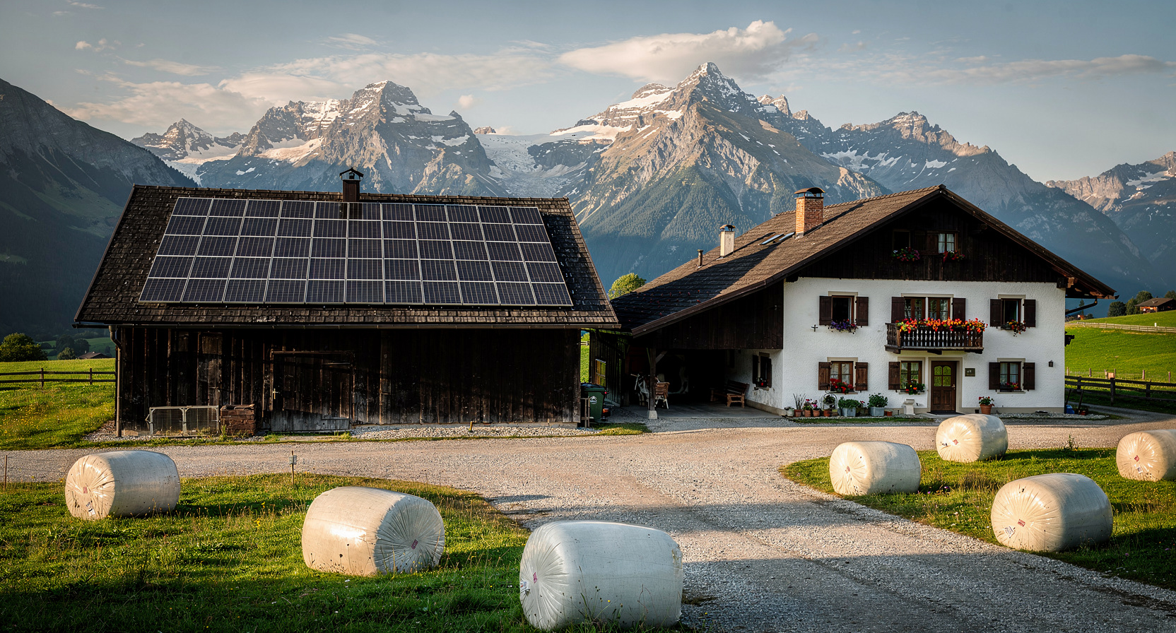 Moderner Tiroler Landwirtschaftsbetrieb mit großflächiger Photovoltaik-Anlage am Stalldach vor Alpenpanorama
